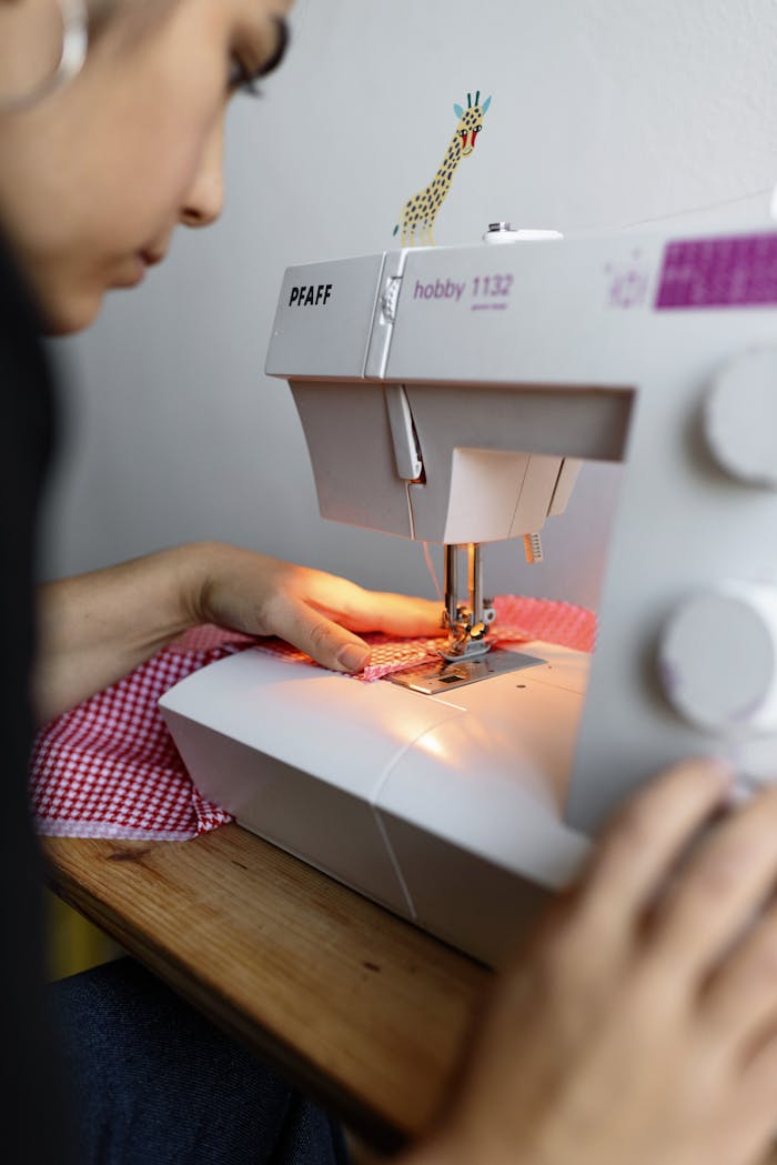 Close-up of a woman sewing fabric on a Pfaff sewing machine in a creative studio setting.
